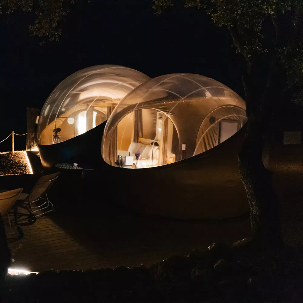 Zwei Bubble Tents erleuchtet bei Nacht.