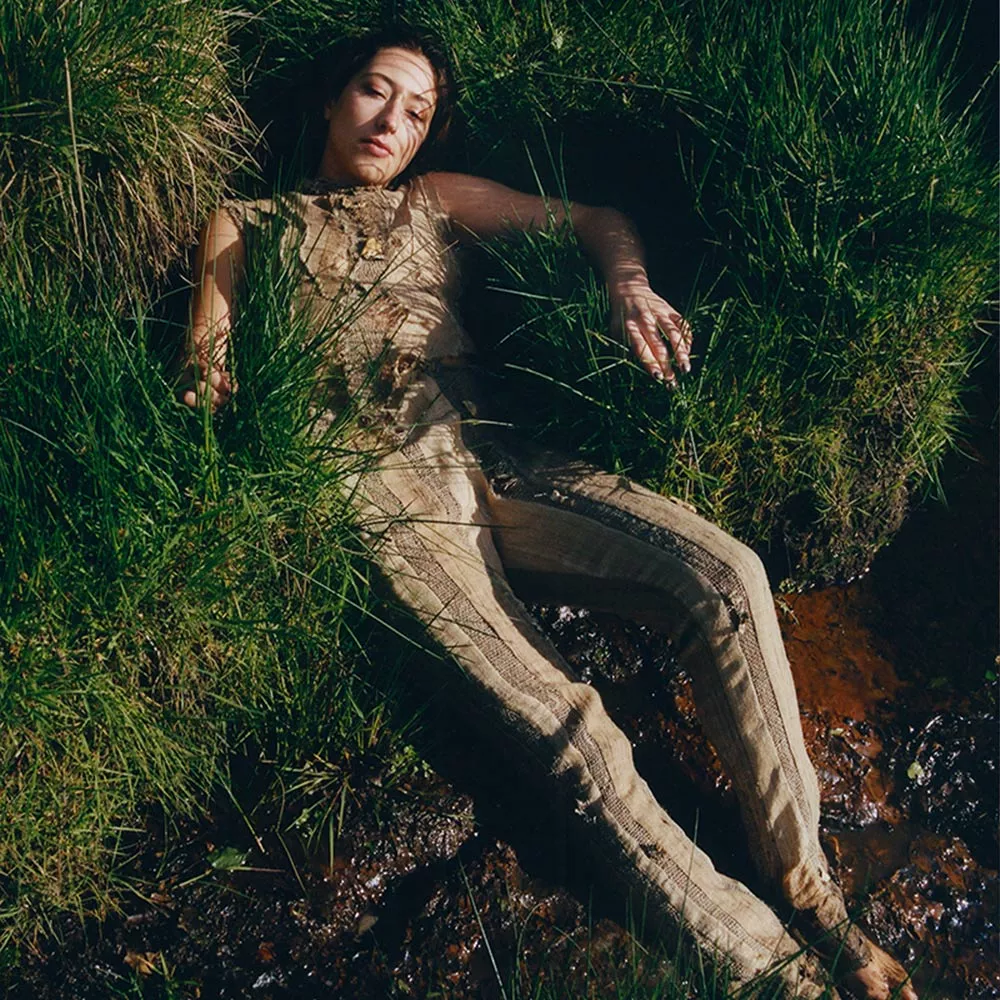 Ein Model liegt mit Helena Elstons Myzel-Kleidung im Gras.
