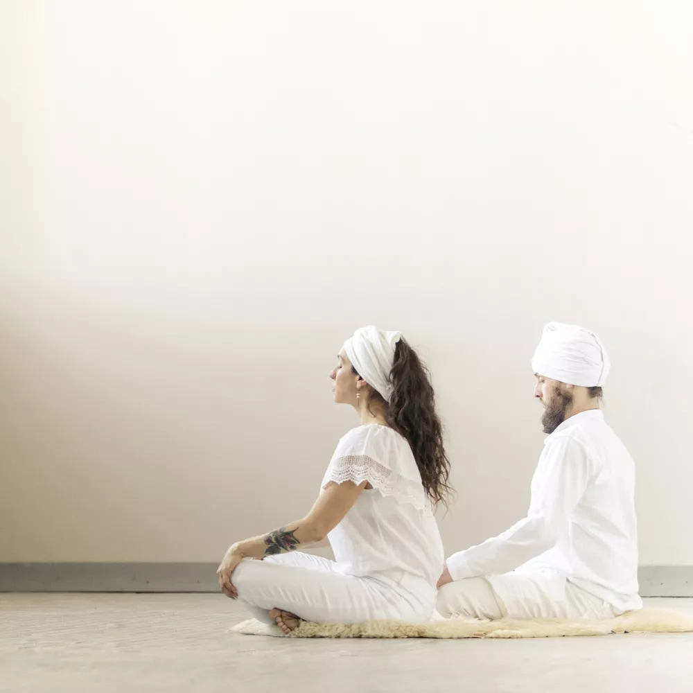 Zwei Menschen praktizieren Kundalini Yoga.