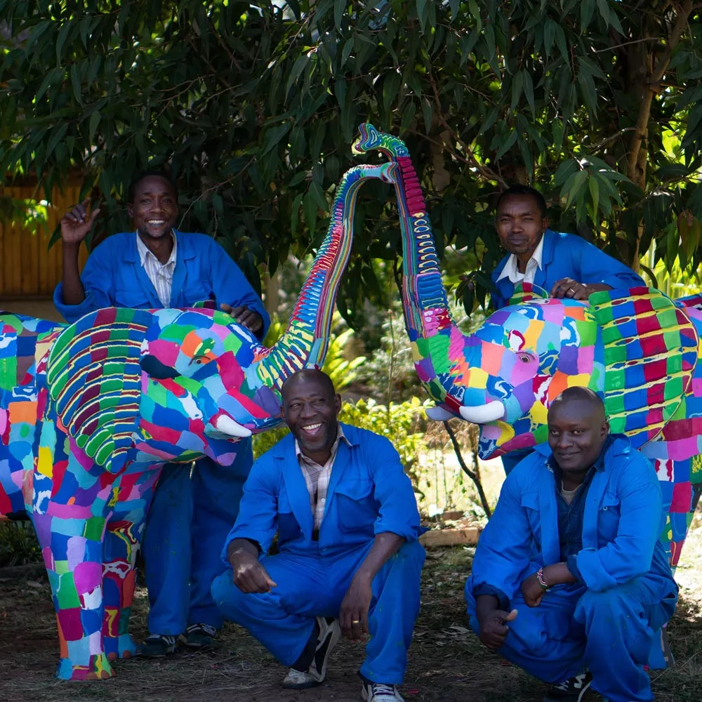 Kunst-Recycling: Handwerkskünstler, die mit ihren Elefant-Kunstwerken vor einem Baum stehen