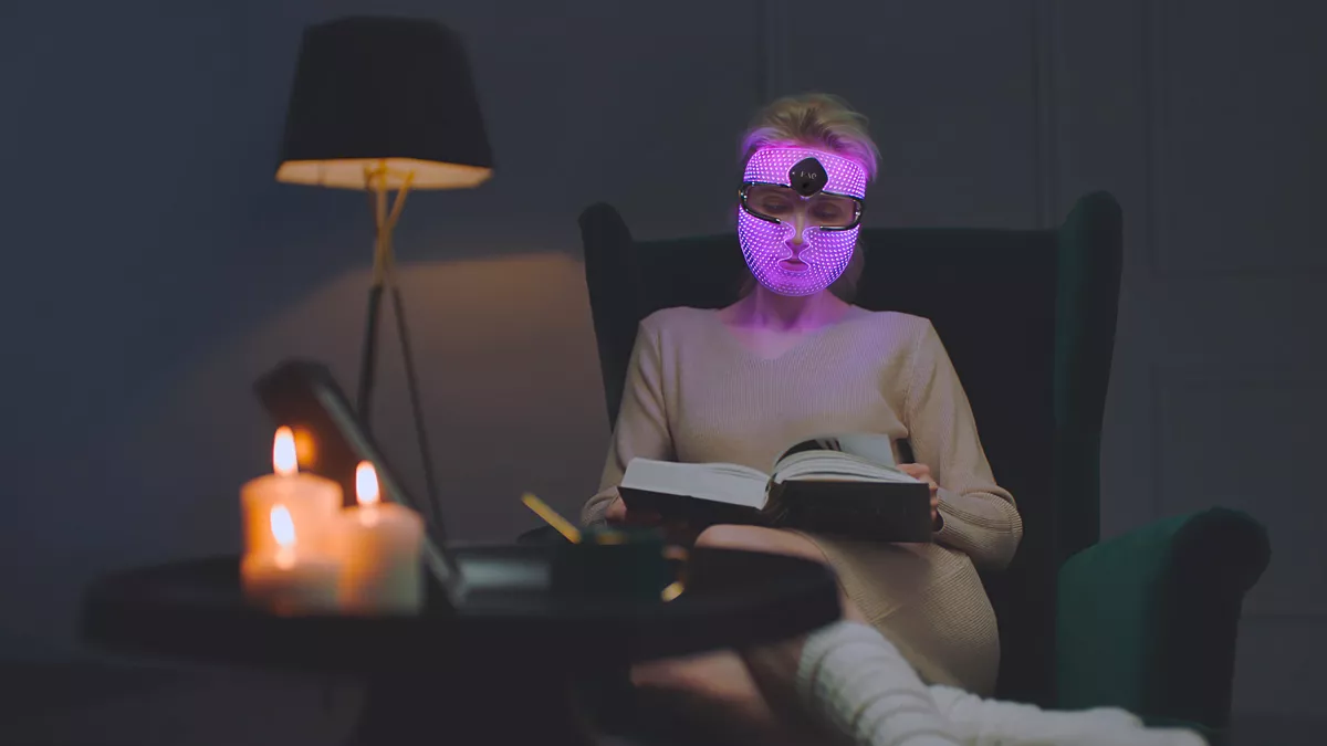 Frau trägt LED-Maske mit lilafarbenen Licht.