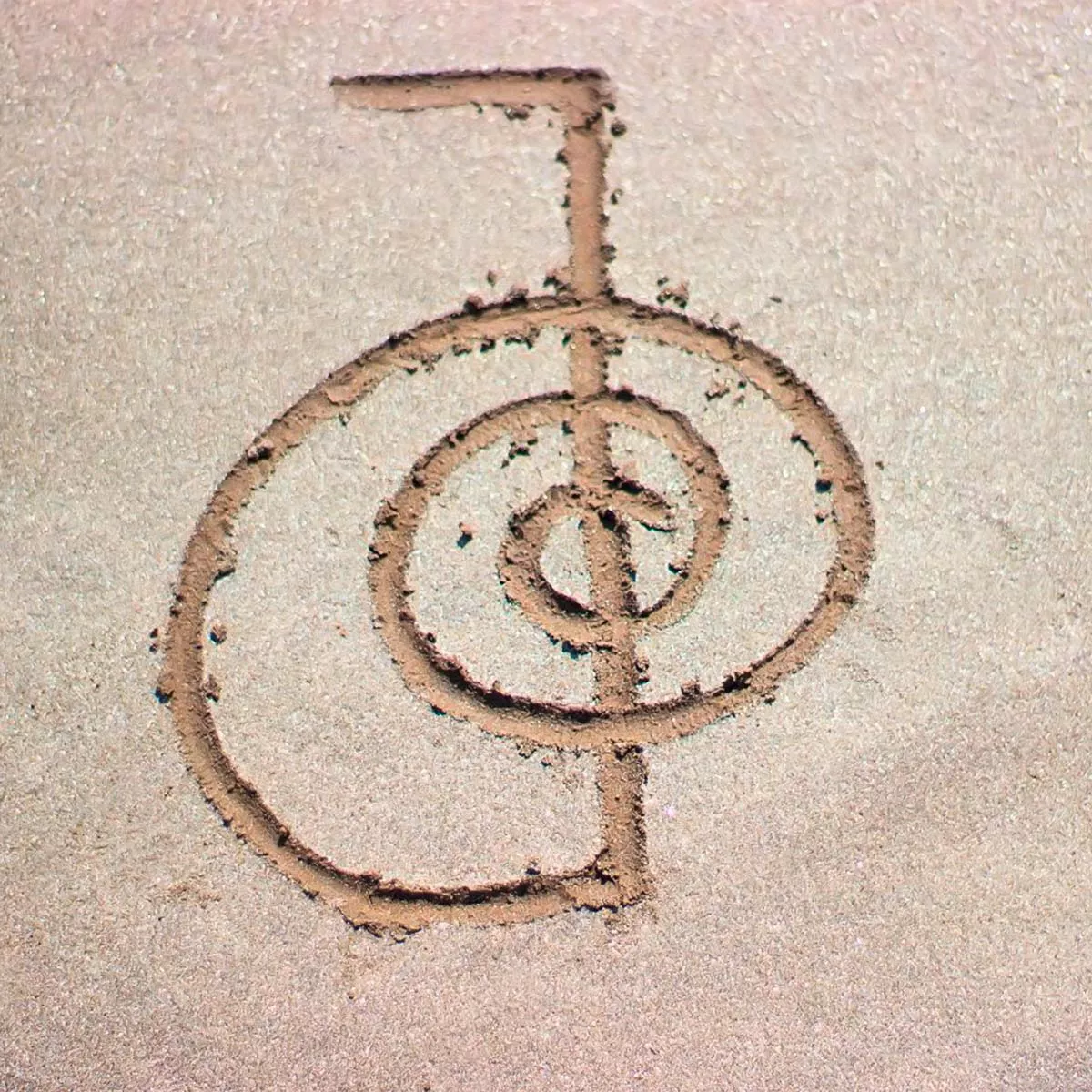 Das Reiki-Meistersymbol in Sand gemalt.