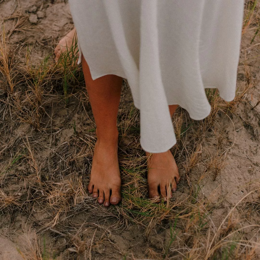 Stress-Detox: Eine Frau steht barfuß auf Sand.