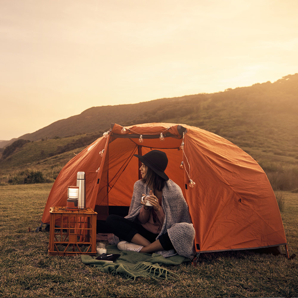 Solar Camping: Frau sitzt am offenen Zelt