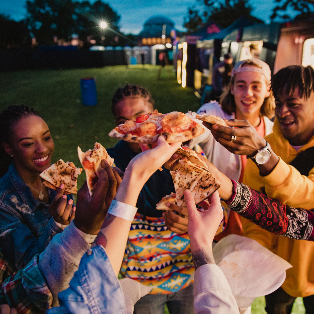 Street Food Festival: Freunde stoßen mit Pizzastücken an