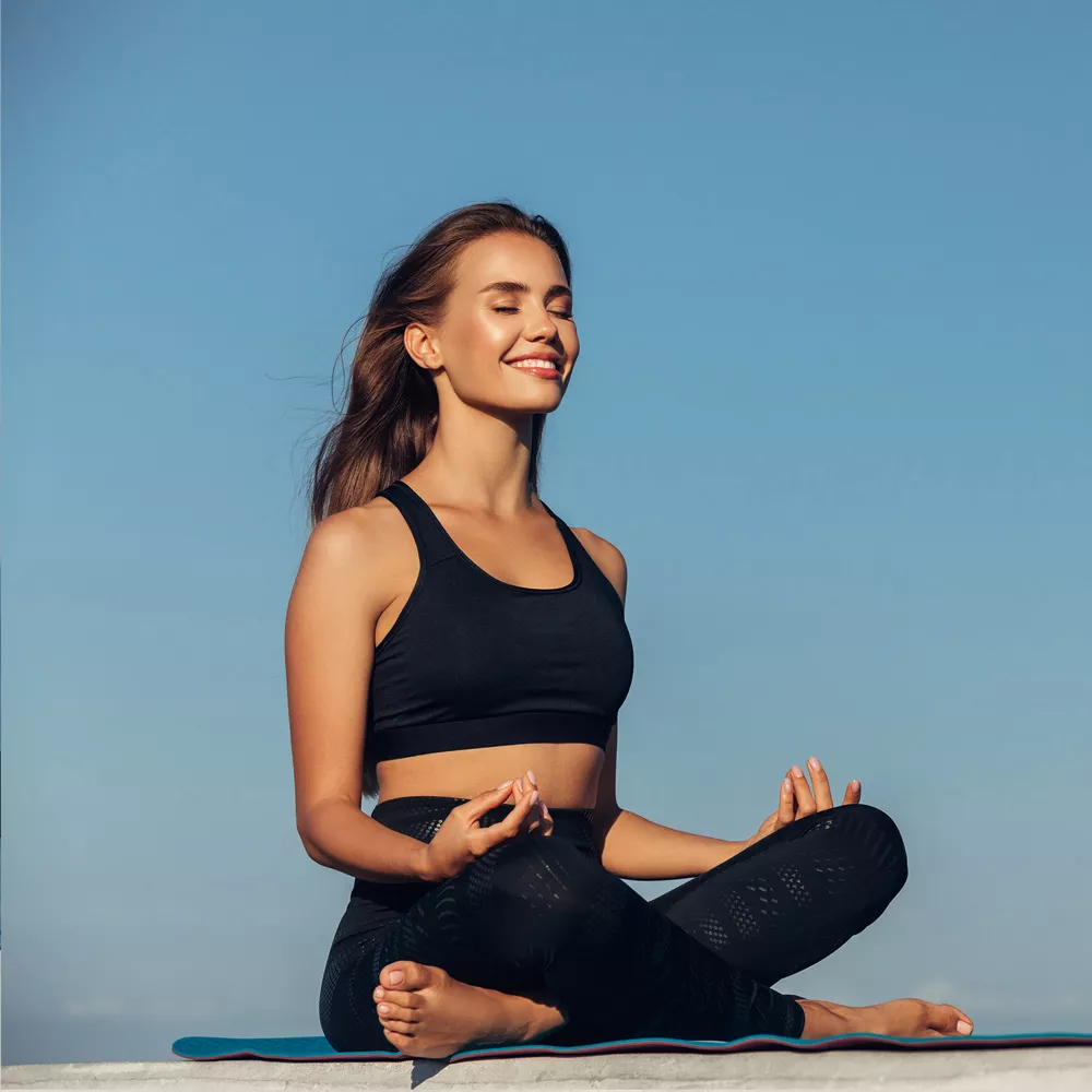 Vinyasa Yoga: Frau meditiert am See