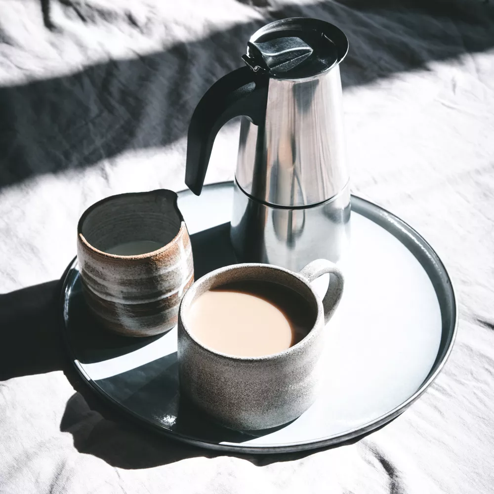 Lagom: Eine Tasse Kaffee und eine Thermoskanne stehen auf einem Tablet.