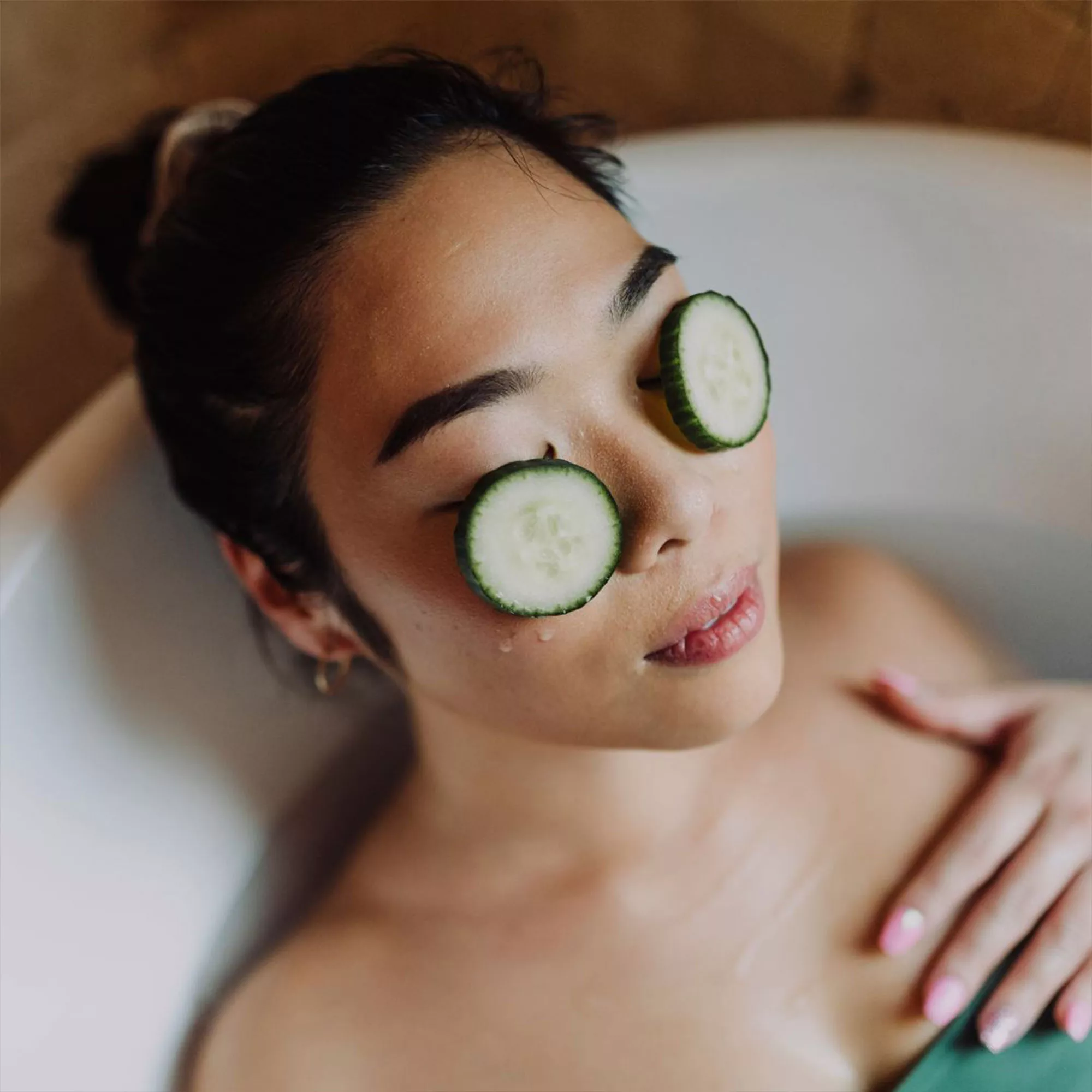 Frau badet mit Gurken auf den Augen als natürliches After Sun