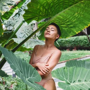 Adaptogene: Eine Frau steht im Badeanzug unter einer großen Pflanze.