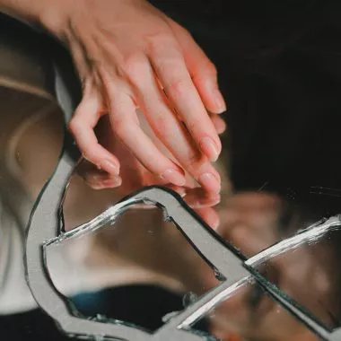 Japanische Maniküre, eine Frau mit natürlichen Nägeln berührt einen zerbrochenen Spiegel.