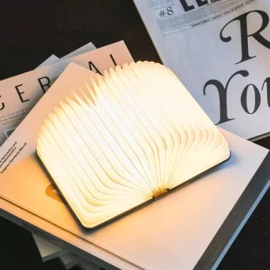 Lito-Mini-Buchlampe von Lumio, halb geöffnet auf Magazinen