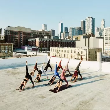 Eine Gruppe übt Power Yoga auf einer Dachterrasse.