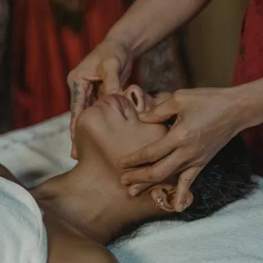 Eine Frau bekommt während einer Reiki-Behandlung die Hände auf das Gesicht gelegt.
