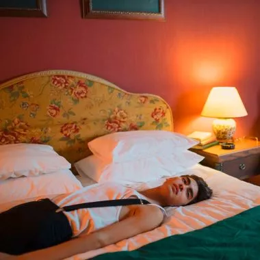 Schlaftoursimus, ein junger Mann liegt in einem Hotelbett.