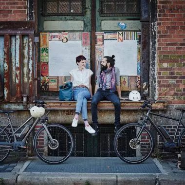 Ein Paar sitzt auf einer Fensterbank mit E-Bikes.