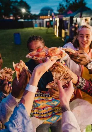 Street Food Festival: Freunde stoßen mit Pizzastücken an