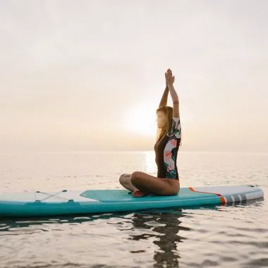 SUP Yoga: Frau macht Yoga auf einem SUP Board