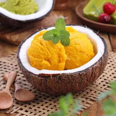 Eine Kokosnuss mit veganer Mango (N)Ice Cream.